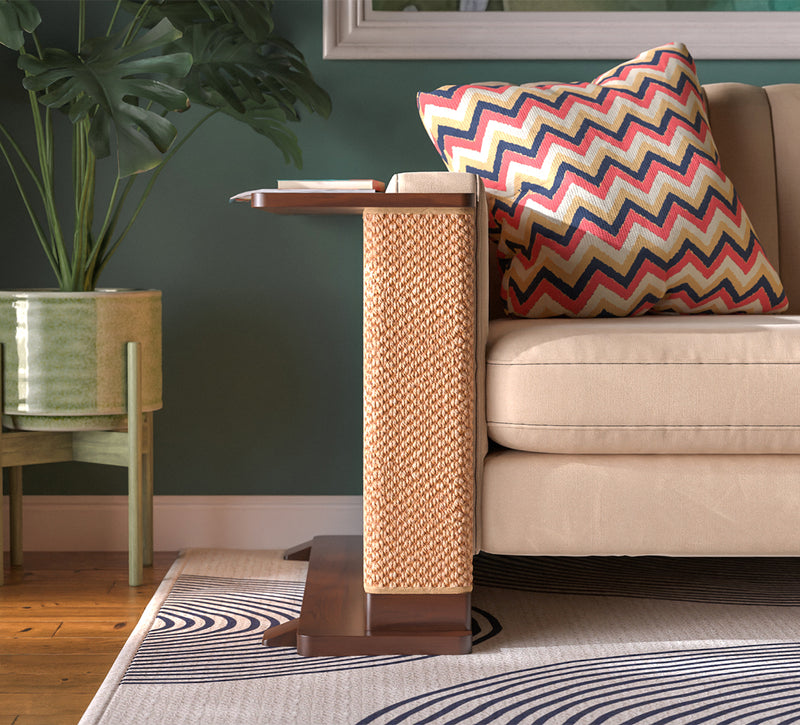 A Cat-e-Corner table placed next to a sofa, integrating a cat's scratching post with a small table, in a room with a plant and a colorful cushion.