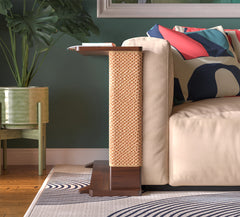 A Cat-e-Corner table placed next to a sofa, integrating a cat's scratching post with a small table, in a room with a plant and a colorful cushion.