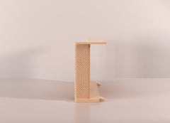 A Cat-e-Corner table placed next to a sofa, integrating a cat's scratching post with a small table, in a room with a plant and a colorful cushion.