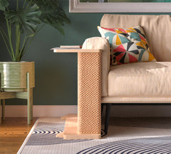 A Cat-e-Corner table placed next to a sofa, integrating a cat's scratching post with a small table, in a room with a plant and a colorful cushion.
