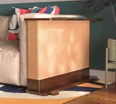 A Cat-e-Corner table placed next to a sofa, integrating a cat's scratching post with a small table, in a room with a plant and a colorful cushion.